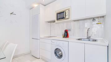 Una cocina moderna con microondas integrado, máquina de café, lavadora y lavaplatos.
