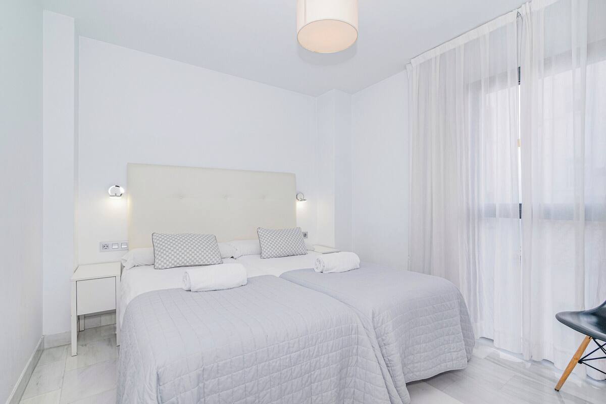 Una habitación de hotel con dos camas, una mesita de noche, una lámpara y una silla.
