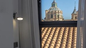 Una camera d'albergo con una grande finestra, un letto e un lampadario a parete.