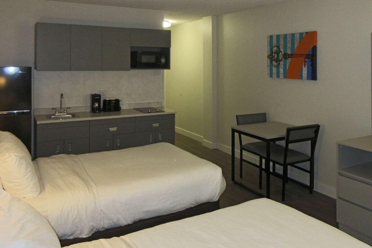 A hotel room with a bed, a desk with a chair, a television, a microwave, and a coffee maker.