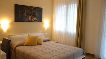 Ein Schlafzimmer mit einem großen Bett, zwei Nachttischlampen, einem Bild an der Wand und einem Fenster mit Vorhängen.