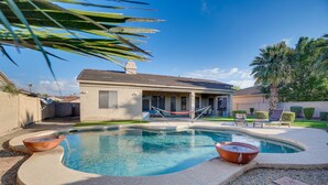 A swimming pool with a curved edge, a hammock, and a house in the background. - Goodyear Group Getaway w/ Pool & Putting Green (Goodyear)