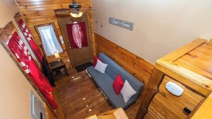 Een knus, houten interieur met een bank, een tafeltje en een bord aan de muur.