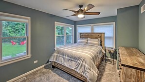 Un dormitorio con cama, ventilador de techo y ventanas amplias.