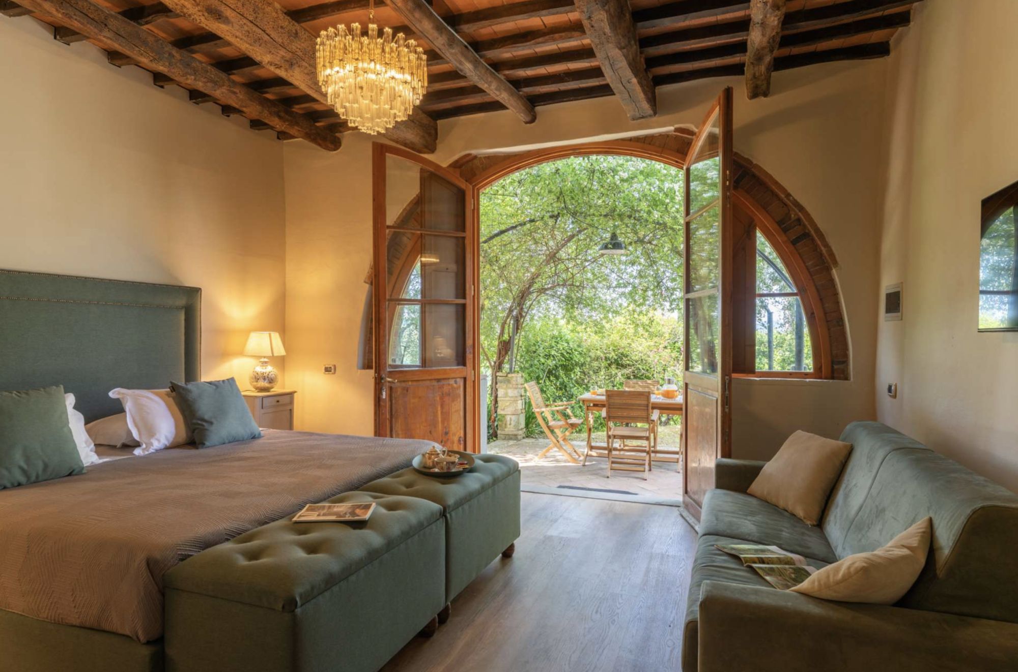 A bedroom with a large bed, a green sofa, and a wooden ceiling.