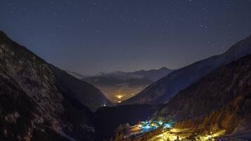 Une vallée enneigée, plongée dans la nuit, avec une ville illuminée par les lampadaires, et entourée de montagnes.