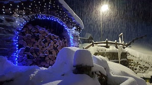 A snow-covered outdoor area with a stone wall, wooden fence, and a snow-covered roof. - Alpe Rebelle (Bionaz)