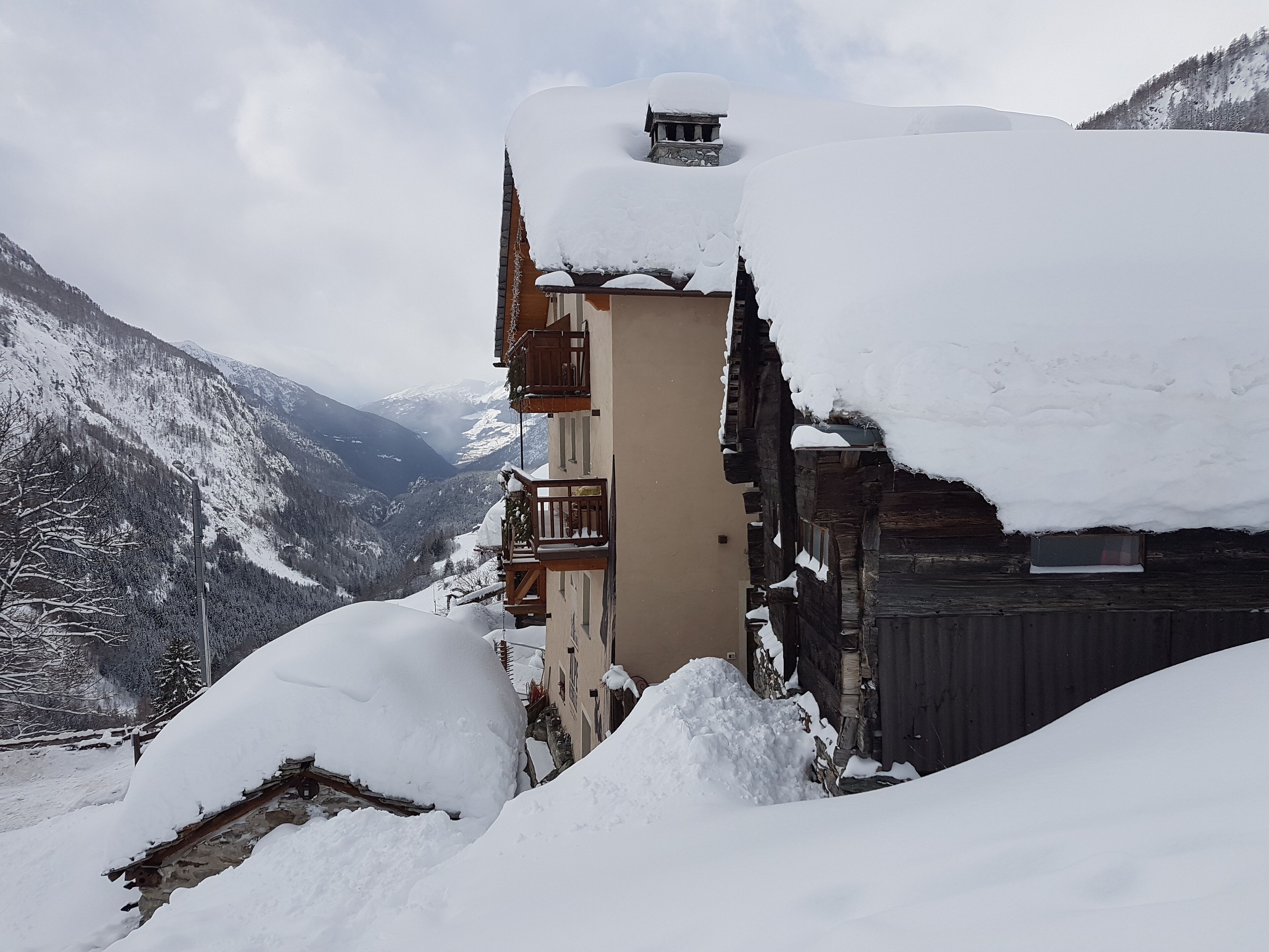 Uma vila montanhosa coberta de neve com edifícios e varandas de madeira tradicionais.