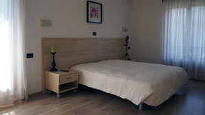 Ein Schlafzimmer mit einem großen Bett, einem Nachttisch, einer Wandleuchte und einem gerahmten Bild.