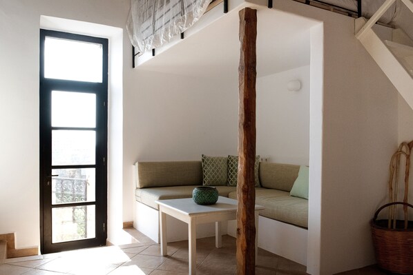 Ein Zimmer mit einem weißen Sofa, einem kleinen Tisch und einer Tür mit einem Fenster.