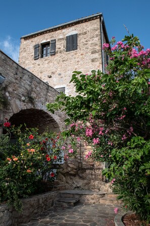 A stone building with a rustic stone archway and a staircase leading to an upper level. - PositiveSpace Olive Tree - A unique tower-house experience (Lefktro)