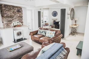A living room with a fireplace, a brown leather sofa, and a grey ottoman.