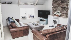 Ein Wohnzimmer mit Ledersofas, Fernseher, Kamin und Steinwand.