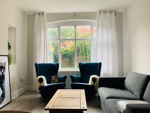 A living room with two blue armchairs, a grey sofa, and a wooden coffee table.