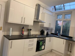A modern kitchen with white cabinets, a black countertop, and a window with a view of trees.