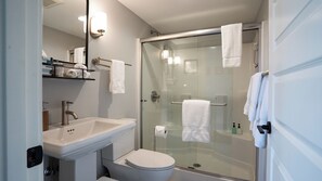 Un baño moderno con ducha de vidrio, lavamanos y retrete.