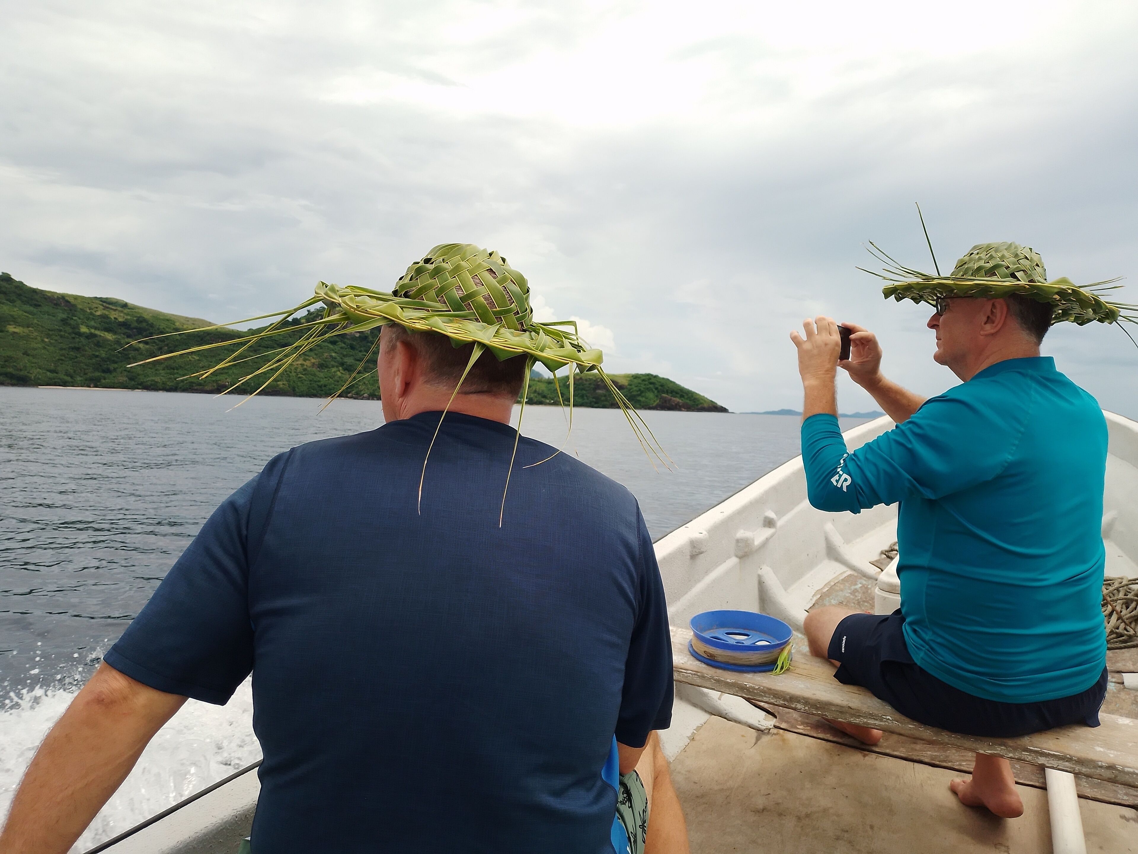 Deux personnes se trouvent sur un bateau, avec une vue sur un lac et des collines.