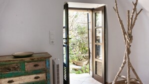 Une pièce avec une commode en bois rustique, un radiateur et une porte donnant sur un jardin.