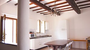 Una cocina con armarios blancos, una mesa de madera y una araña.
