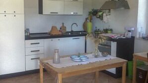 Una cocina con armarios blancos, encimera negra y mesa de madera con un jarrón y cuencos.
