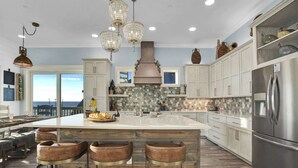 A spacious kitchen with a large island, bar stools, and a view of the ocean.