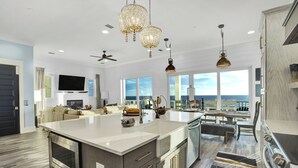 A spacious kitchen with a large island, modern appliances, and a view of the ocean.