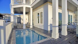 A poolside area with a pool, deck chairs, and a covered seating area.