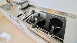 A kitchen with a stove, pots, a frying pan, a spatula, and a toaster.