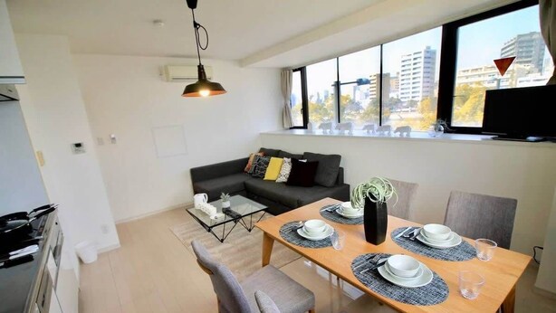 A modern living room with a dining area, a sofa, a coffee table, and a TV.