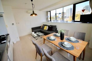 A modern living room with a dining area, a sofa, a coffee table, and a TV.
