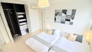 A bedroom with two beds, a wardrobe, and a wall art piece.