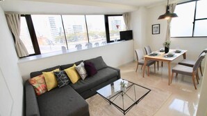 A modern living room with a sofa, coffee table, dining table, and chairs.