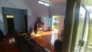 A living room with a sofa, a bookshelf, and a door leading to a balcony.
