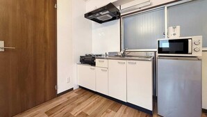 A compact kitchen with a microwave, stove, and built-in oven. - 1 Bedrm Apt 5mins from Hiroshima Sta  5ppl (302) (Hiroshima City)