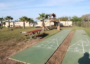 A park with a shuffleboard table, picnic table, and playground equipment. - Summerhouse 228 (St. Augustine)
