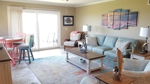 A living room with a sofa, armchairs, a coffee table, and a dining area with chairs and a table. - Summerhouse 101 (St. Augustine)