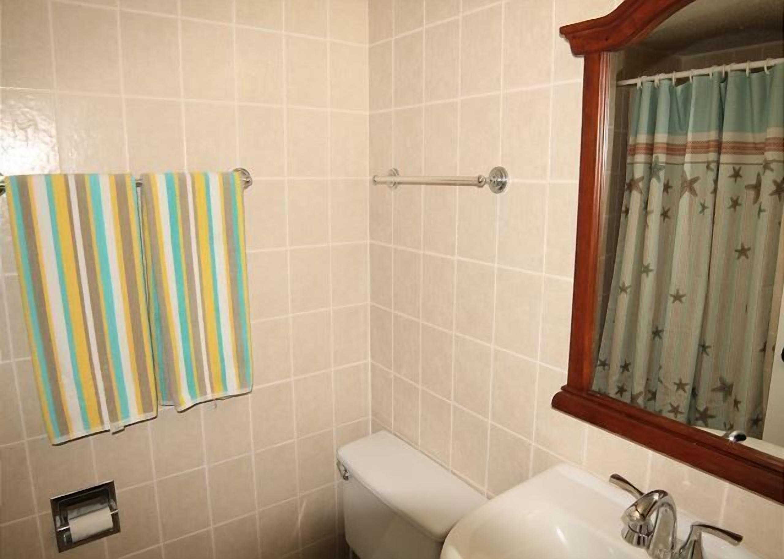 Une salle de bain avec des toilettes, un lavabo et une fenêtre avec des rideaux.
