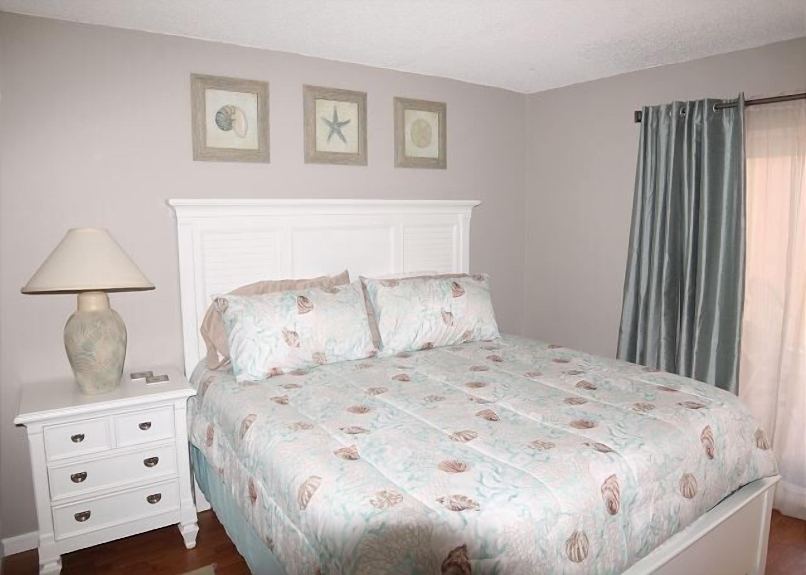 A bedroom with a bed, nightstand, and wall art.