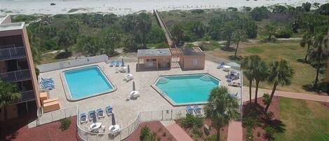 A resort with two swimming pools, a beach view, and a parking area.