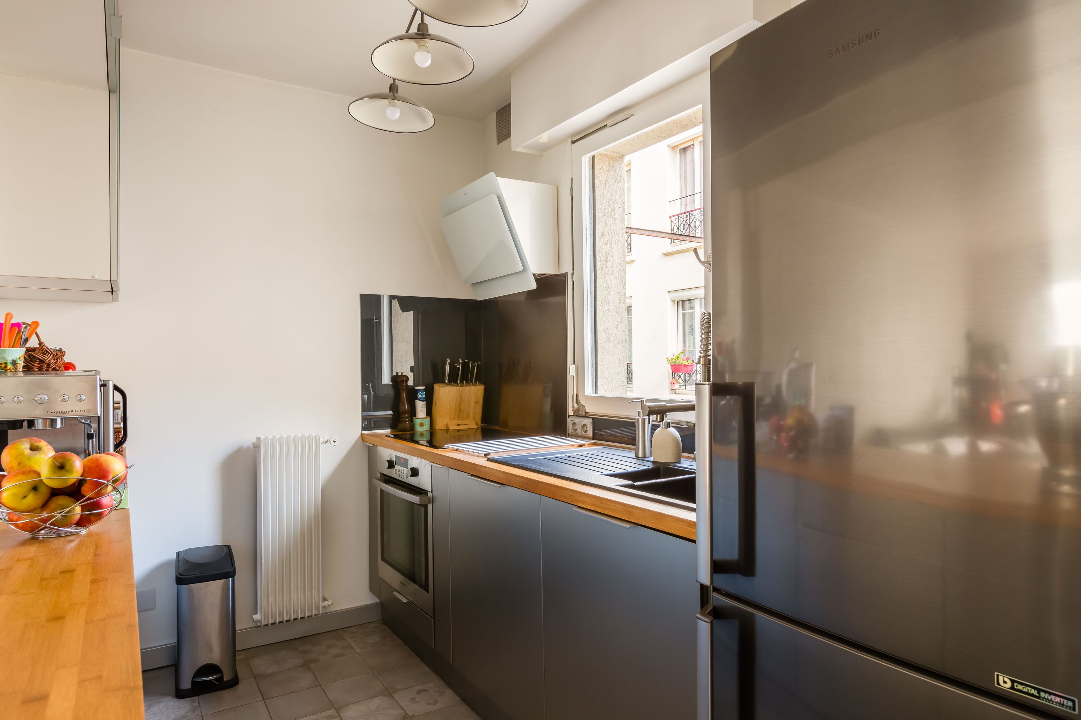 A modern kitchen with a stainless steel refrigerator, a built-in oven, and a window providing natural light.