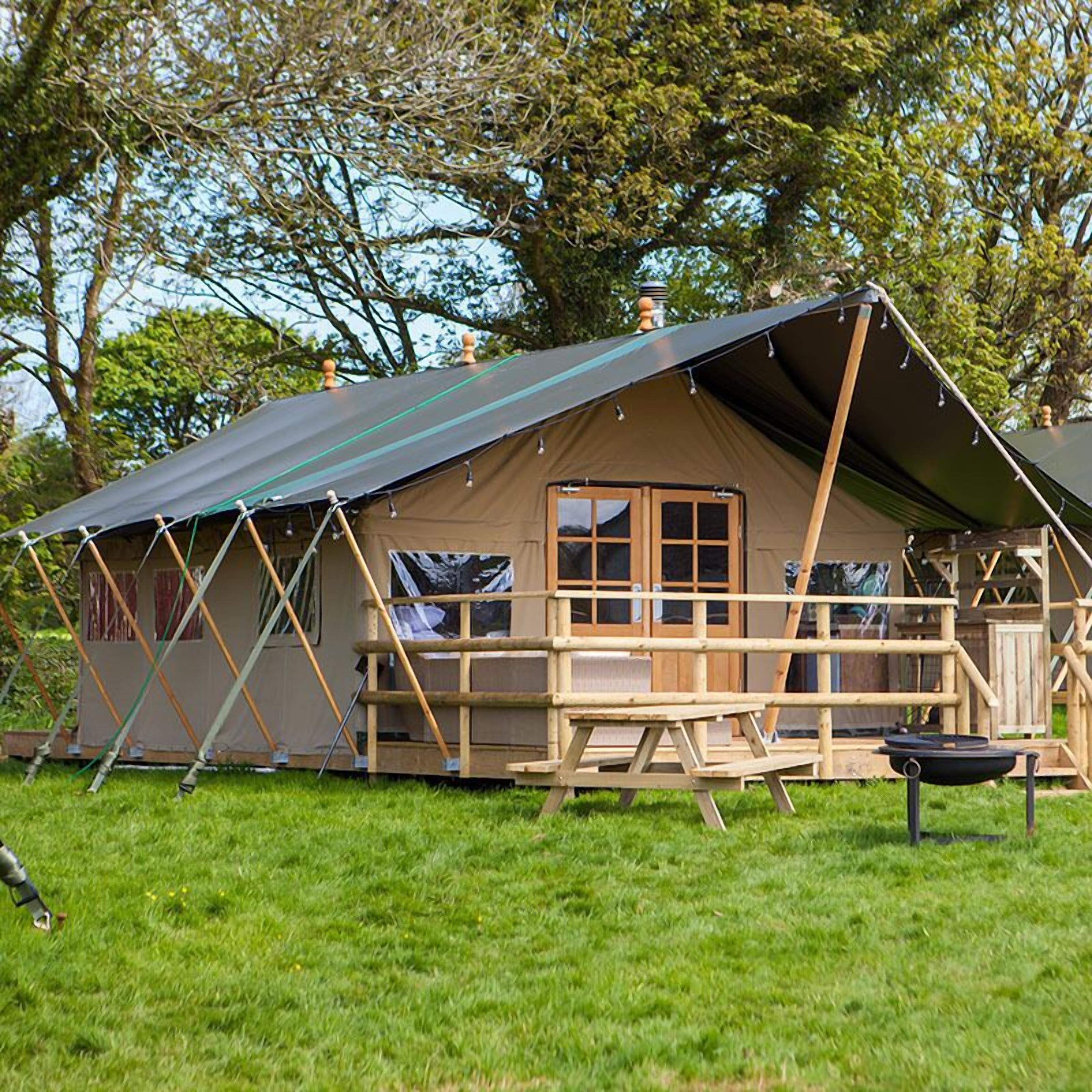 A tent with a wooden deck and a chimney.
