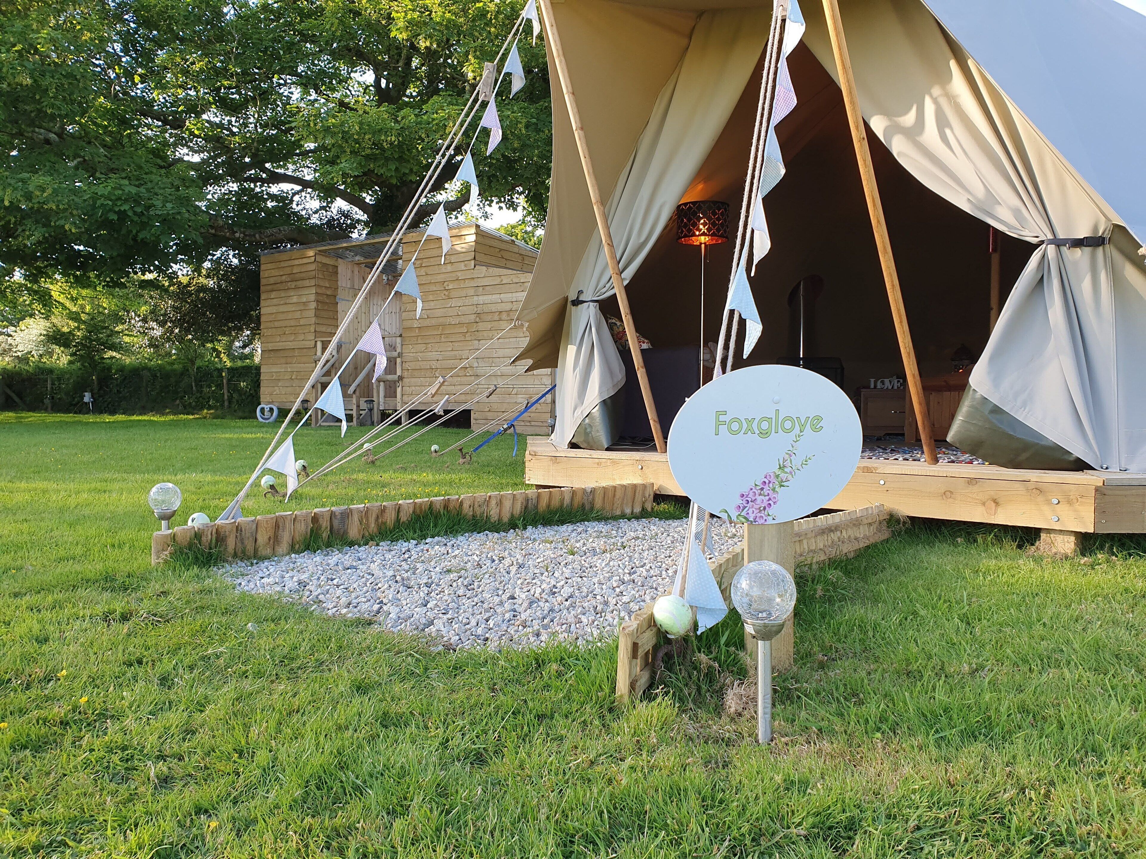 A rustic wooden structure with a sign reading "Foxglove" and a tent in the background.