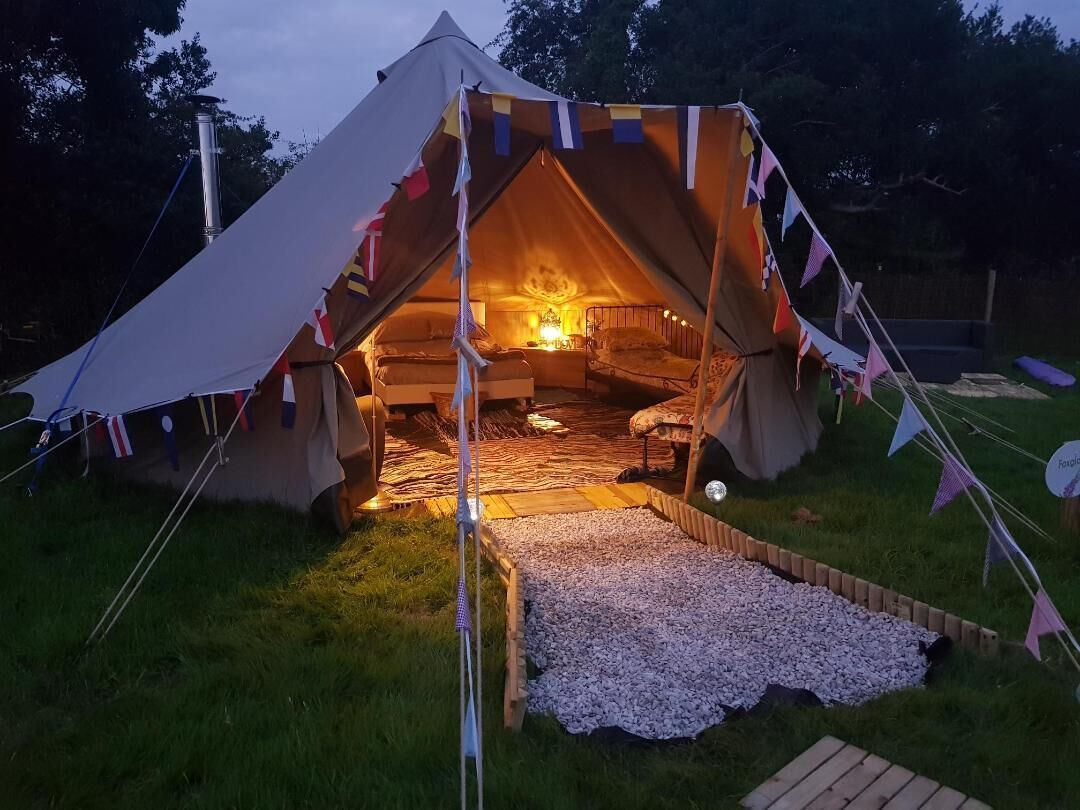 Une tente dotée d’un éclairage intérieur chaleureux, d’un lit et d’une petite table.