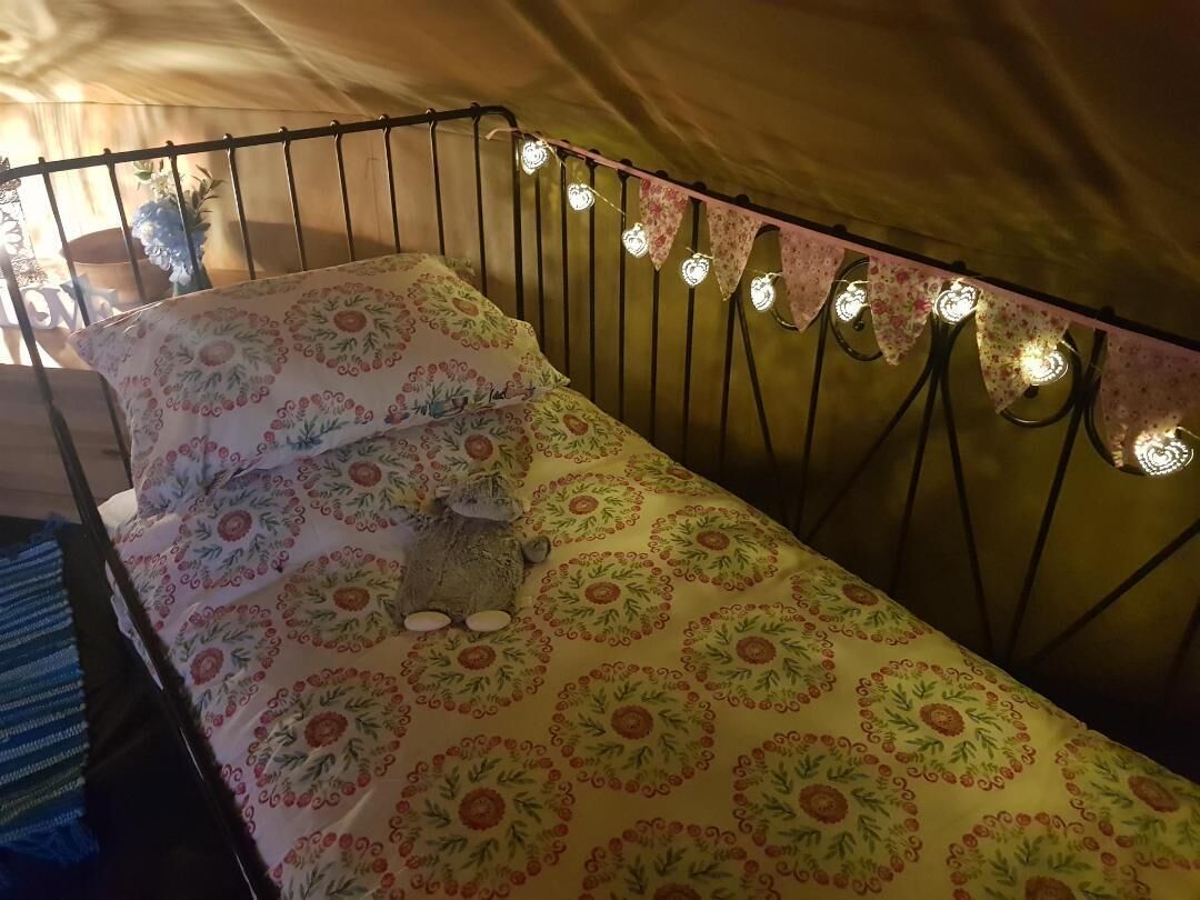 A bed with floral bedding and a headboard with lights.