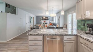 A modern kitchen with a marble countertop, stainless steel appliances, and pendant lighting. - Upscale House with Outdoor Seating/Firepit (Boise)