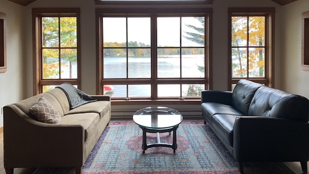 A living room with a large window, a ceiling fan, and two sofas. - The Landing on Lake Nebagamon - Includes Pontoon! (Lake Nebagamon)