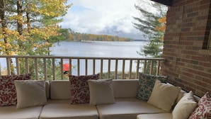 A covered outdoor seating area with a view of a lake and autumn foliage. - The Landing on Lake Nebagamon - Includes Pontoon! (Lake Nebagamon)