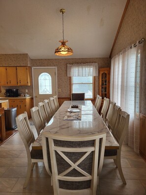 Un comedor con una mesa de mármol, sillas de madera y una lámpara colgante.