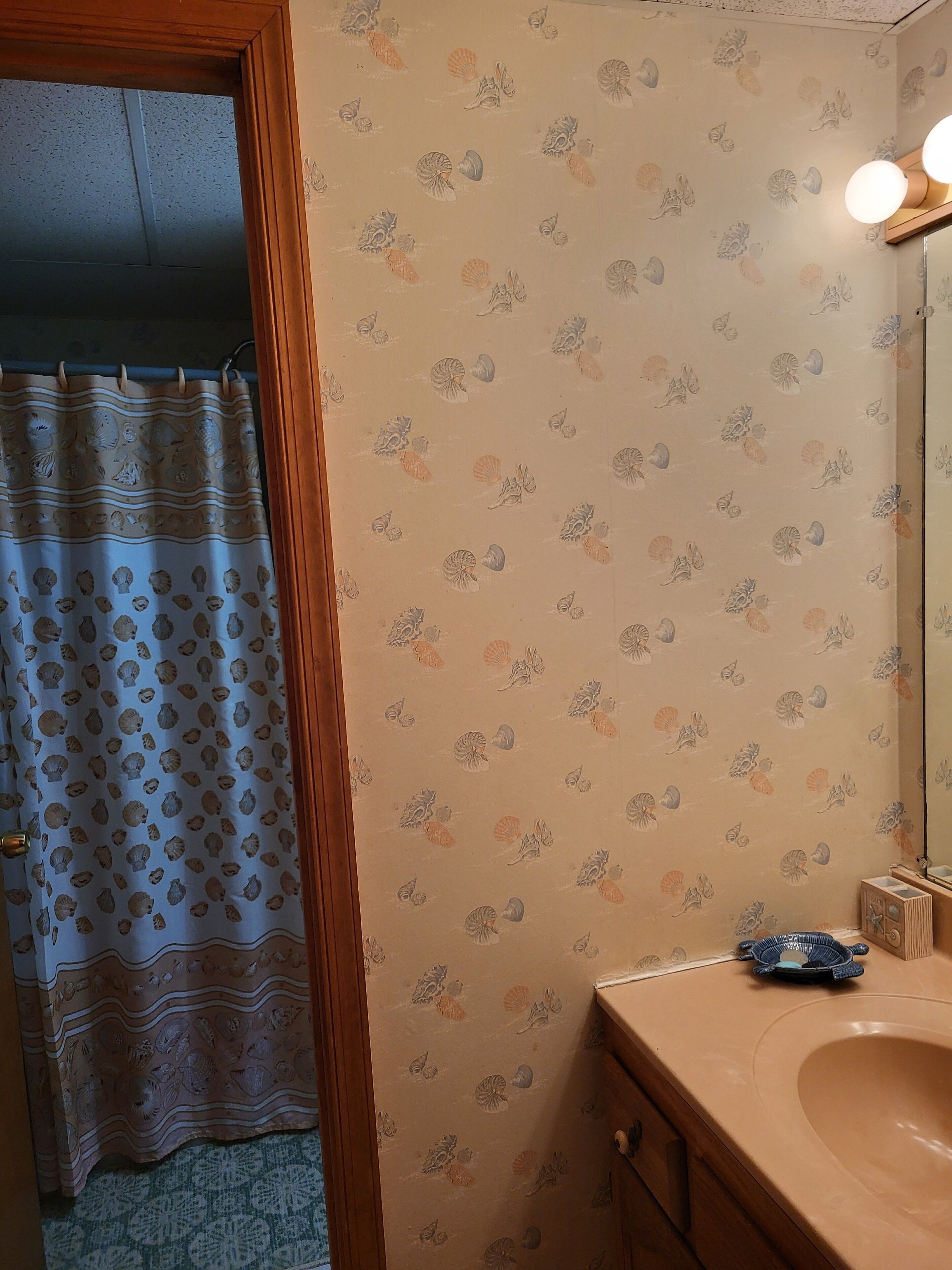 A bathroom with a beige sink, a mirror, and a shower curtain with a polka dot pattern.