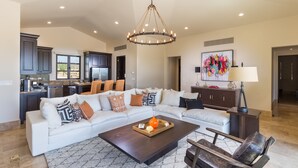 A spacious living room with a sectional sofa, a coffee table, and a chandelier.